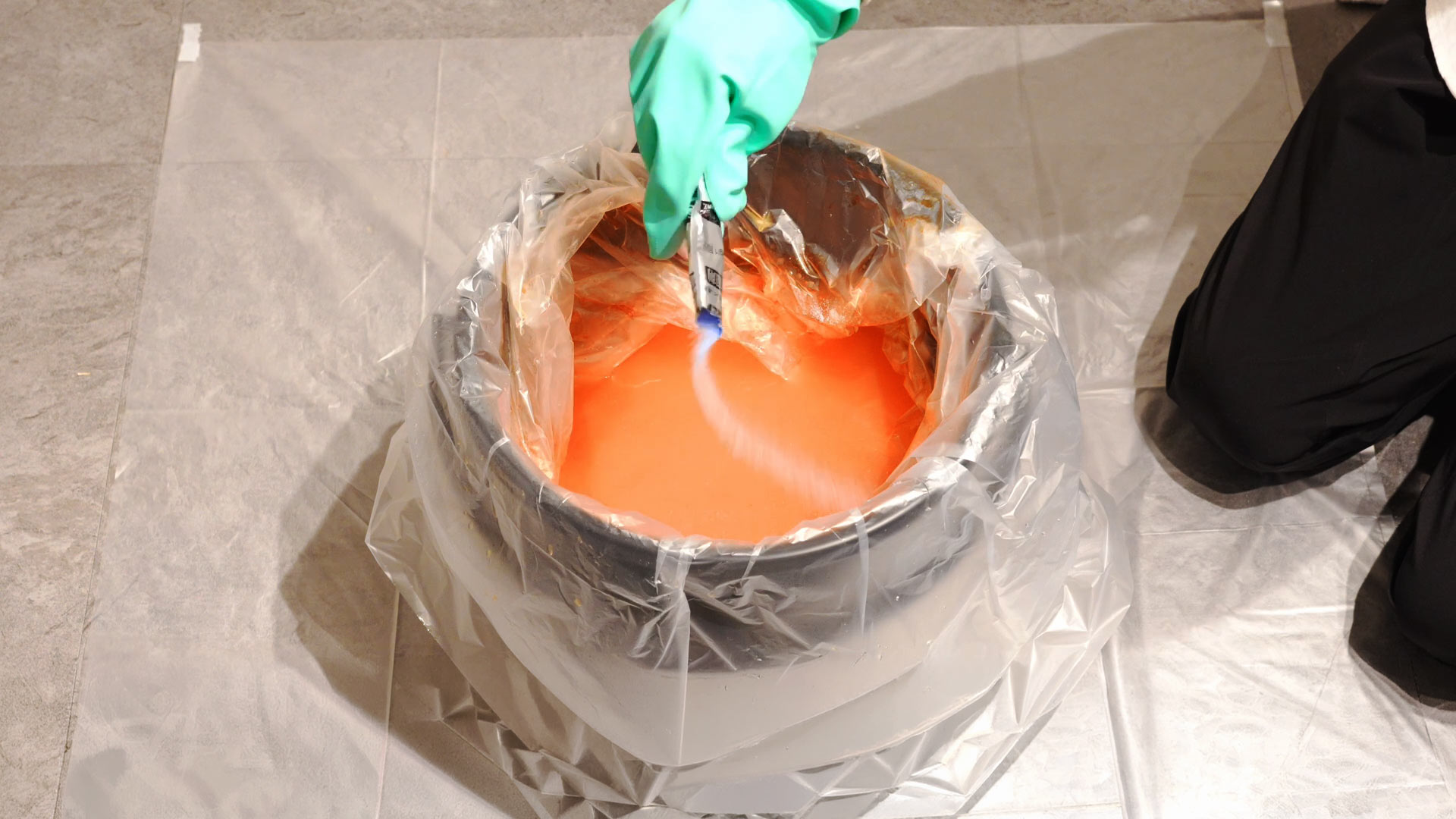 熊スプレー廃棄処理・凝固剤の使用。バケツ内の液体に凝固剤を投入してゼリー状に固める様子。