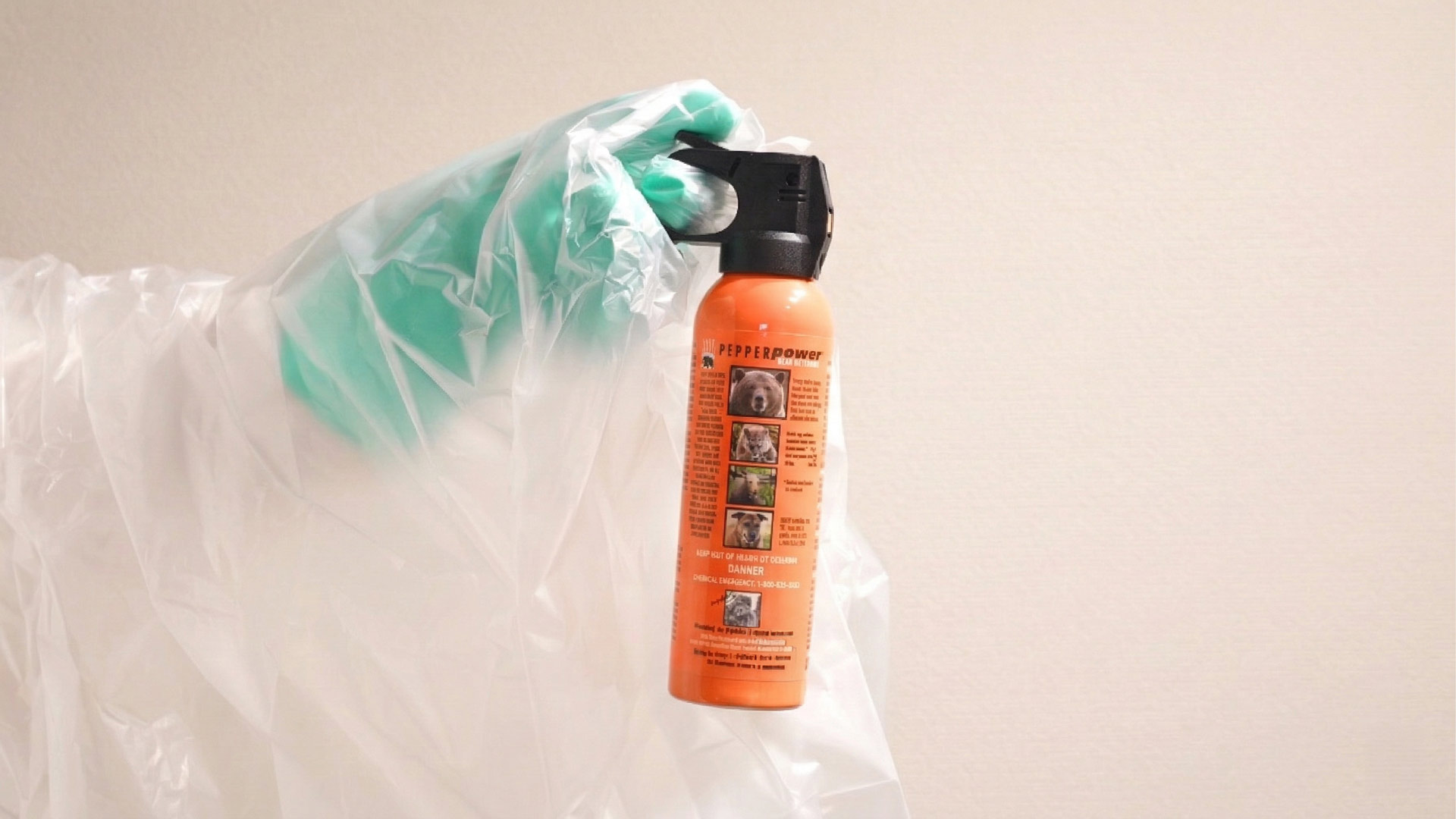 熊スプレー廃棄手順・缶の持ち方。安全クリップを抜き、腕をポリ袋で保護しながら本体を握る様子。