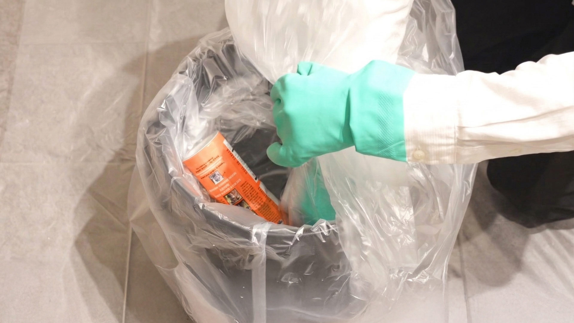 熊スプレー廃棄手順・水中への投入。噴射口を下向きにしてスプレー缶を水に沈め、ポリ袋で覆う様子。