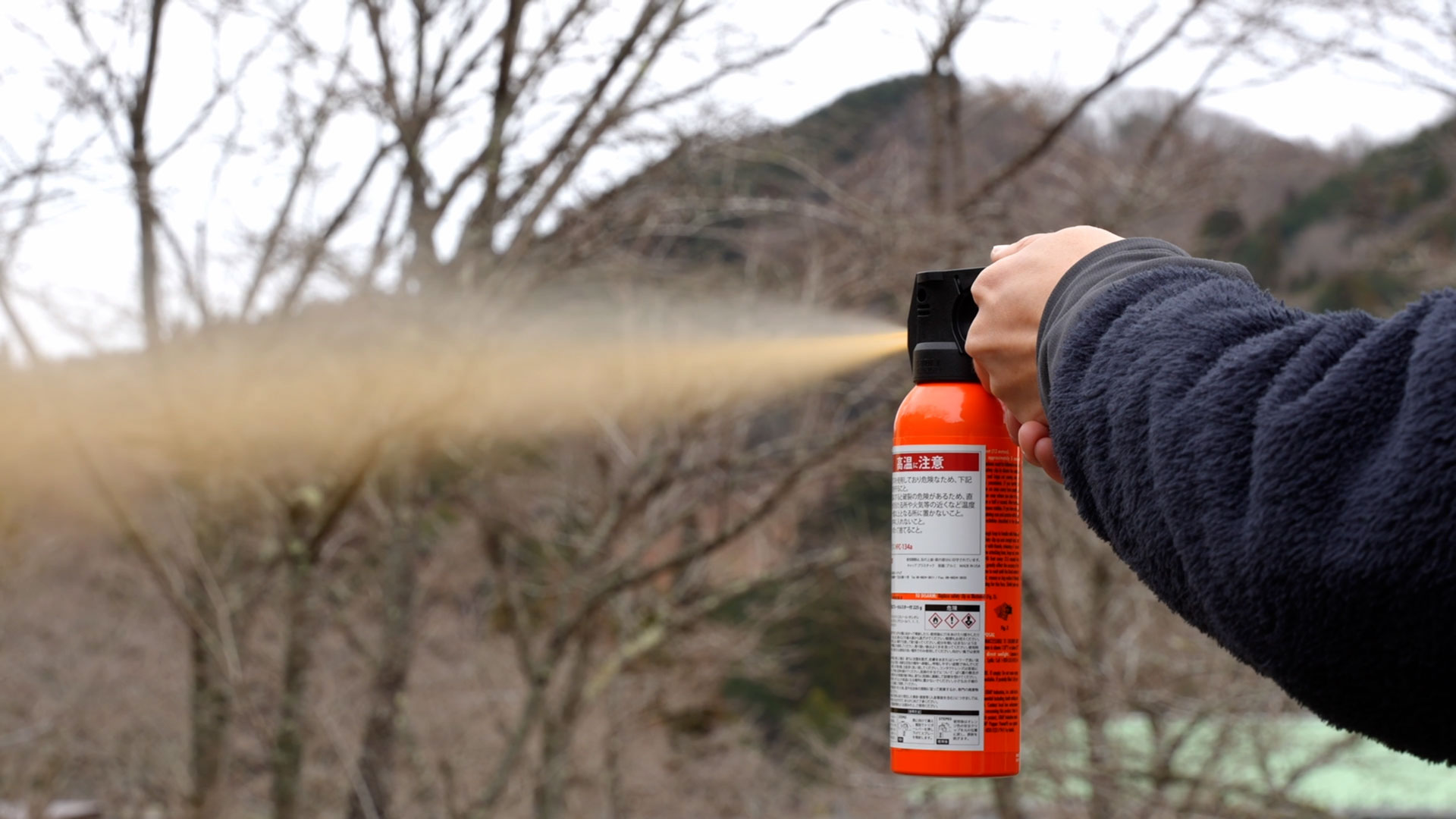 熊スプレーを屋外で実際に噴射している実写写真。広範囲に霧状のスプレーが拡散する様子。
